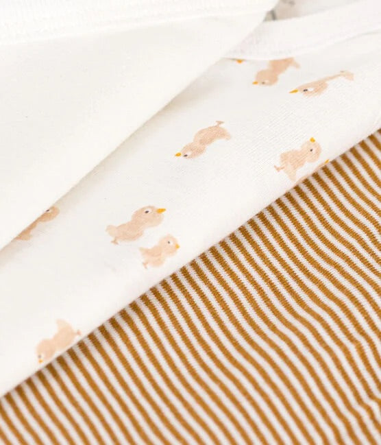 3 tissus superposés, un blanc, un blanc à motifs de poussins jaune et un brun ligné blanc.