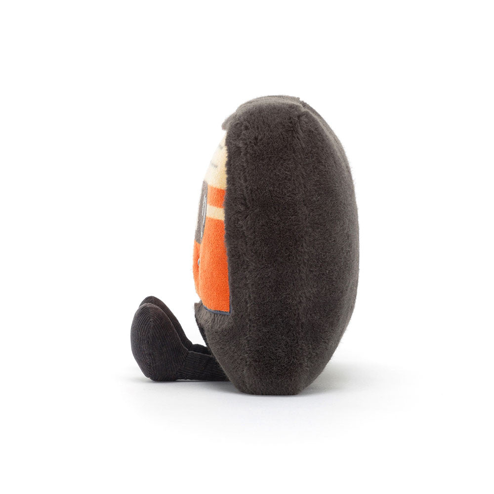 Peluche en forme de cassette retro orange avec un visage souriant et des jambes assises vue de coté.