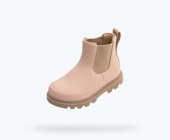 Une botte Chelsea rose millennial avec semelle et panneaux élastiques bruns.