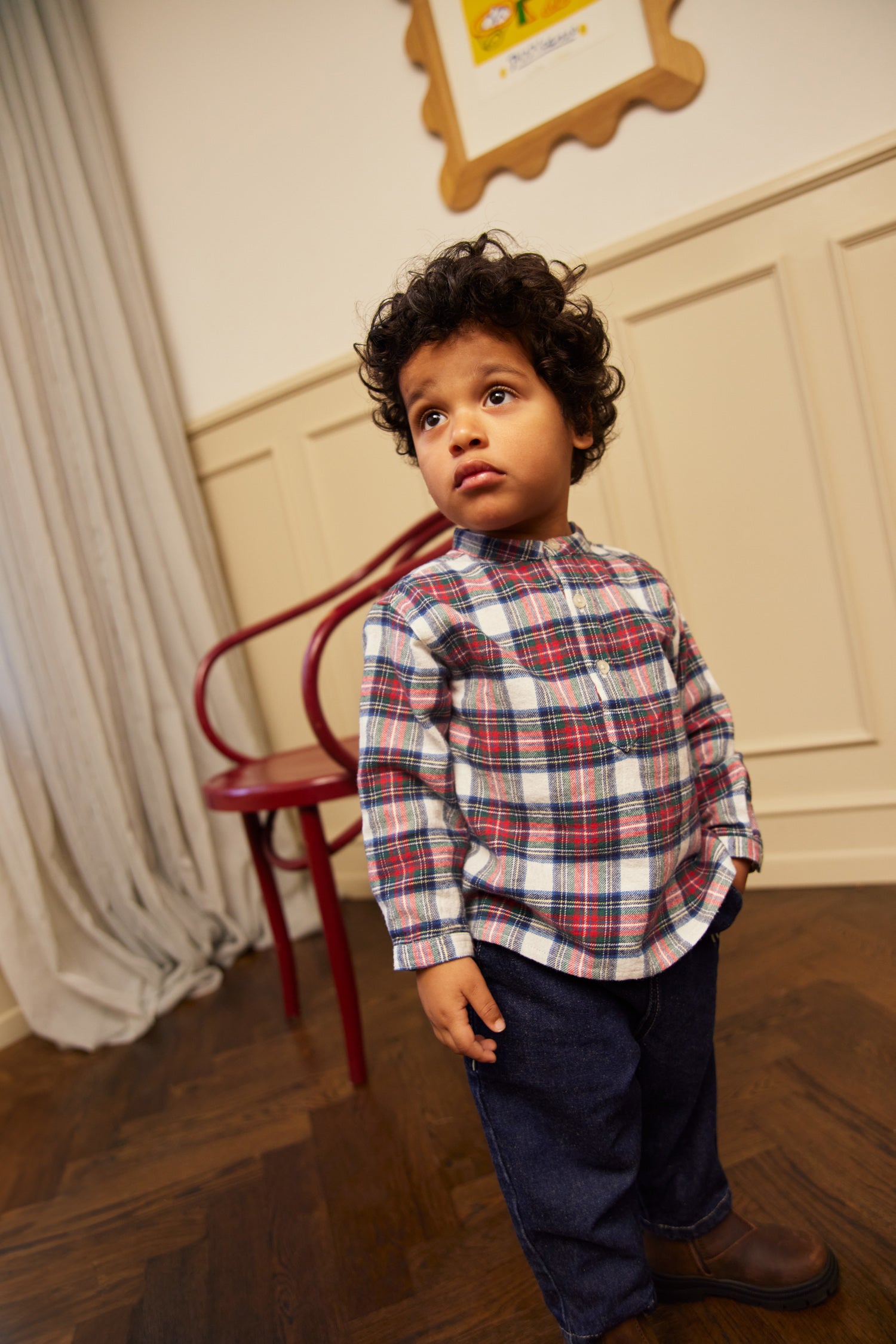 Un garçon portant une chemise à carreaux rouge, vert et blanc.