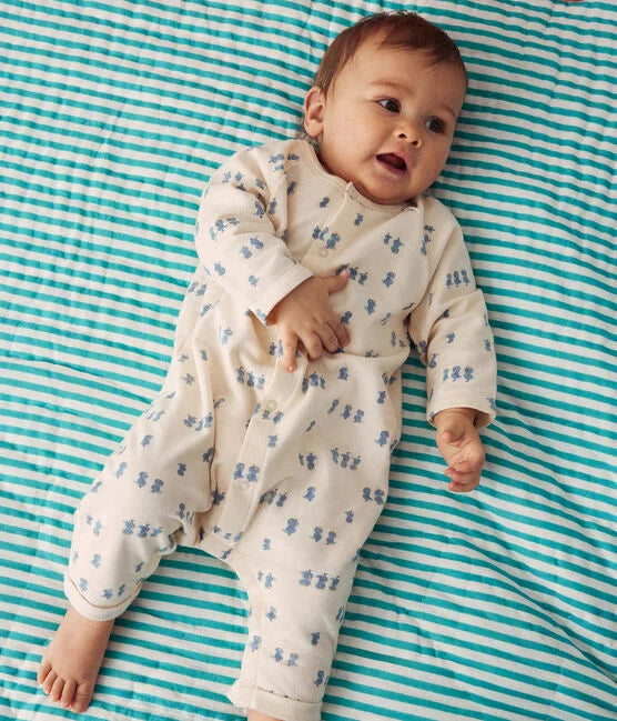 Une combinaison pyjama beige pour bébé avec un motif d'illustration d'oiseaux bleus.