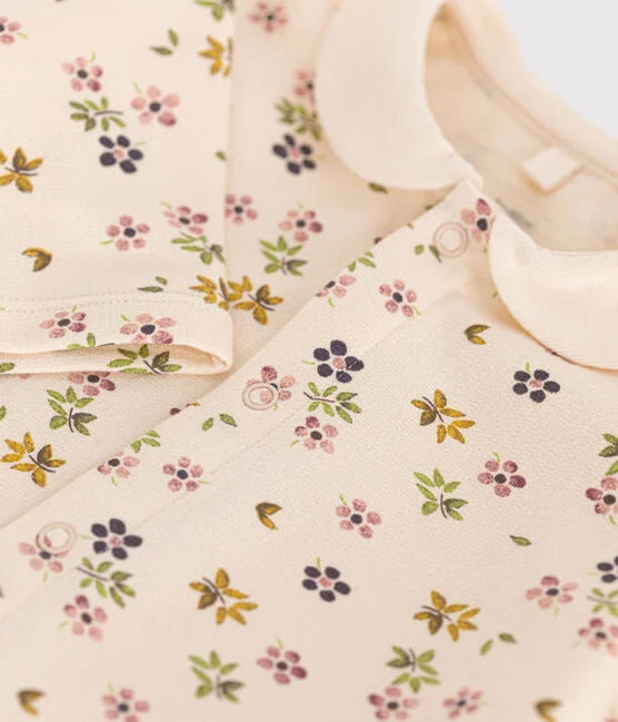 Une combinaison à manches longues beige avec motif fleuri rosé, bleu et vert. Un col claudine.