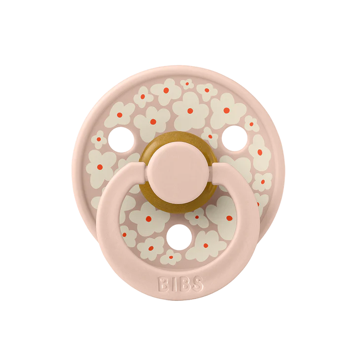 Une suce rose pâle, avec motif de fleurs blanches sur le disque.
