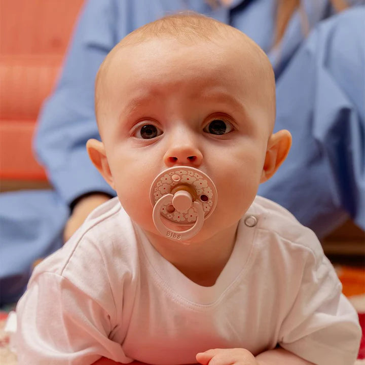 Un bébé utilisant suce rose pâle