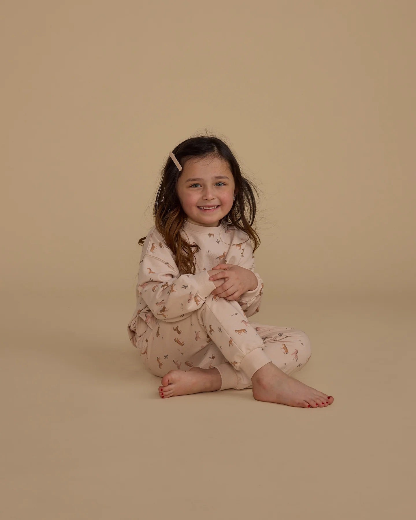 Une fillette portant un ensemble de pantalon et chandail rose à motif de chaux.