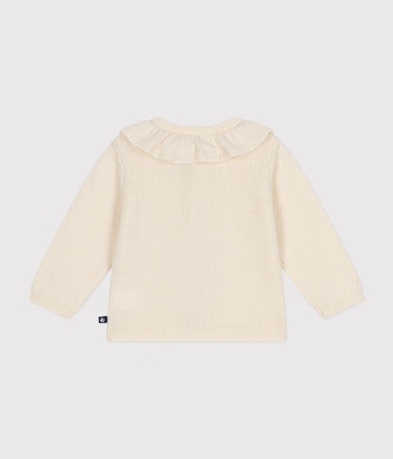 Un cardigan en tricot blanc avec col à petits volants.