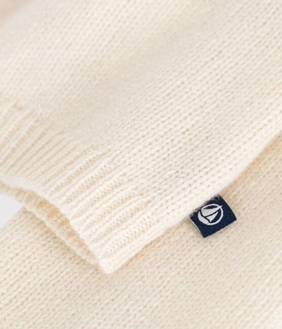 Un cardigan en tricot blanc avec petite étiquette de Petit Bateau bleu.