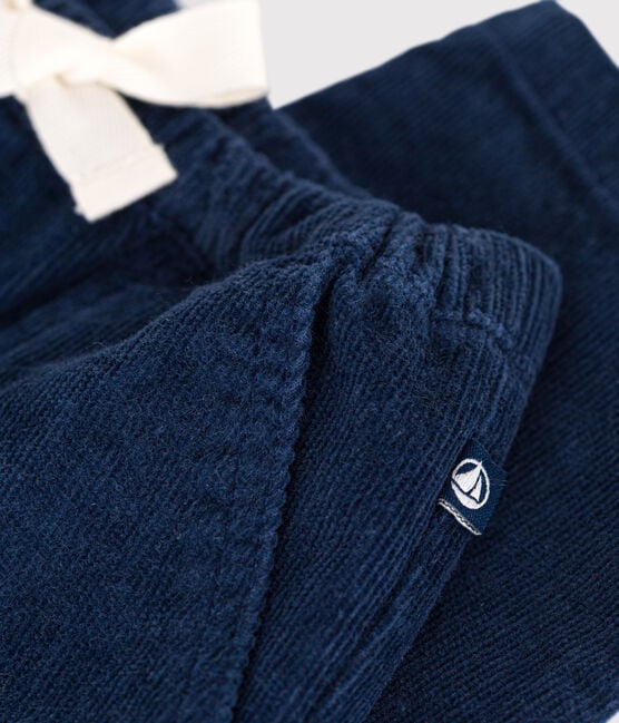Un pantalon pour bébé en velours côtelé bleu marine avec poches et petite étiquette Petit Bateau.