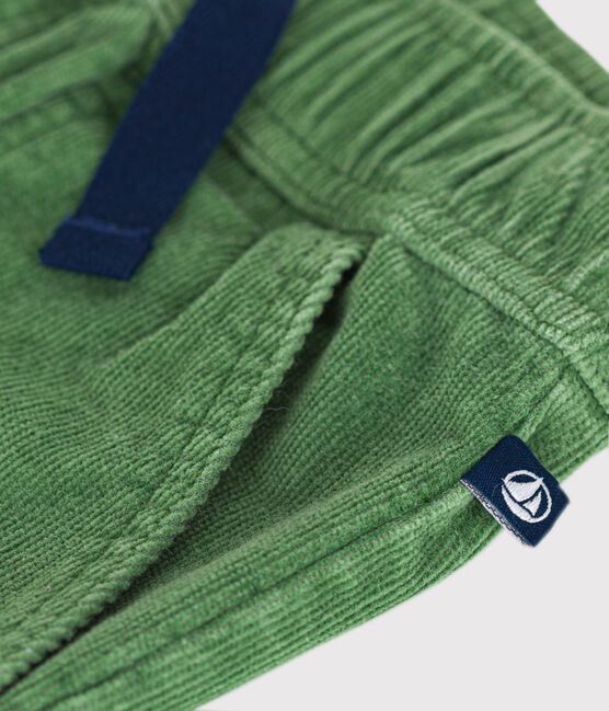 Un pantalon en velours côtelé vert, avec taille élastique et lacet noir ajustable, et poches.