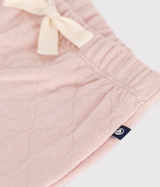 Un pantalon rose pâle à taille élastique et lacet blanc ajustable.