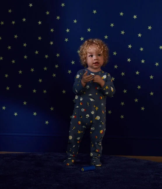 Un pyjama une pièce long bleu, avec motif d'illustration d'étoiles et de planètes.