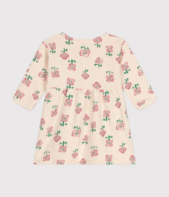Une robe pour bébé à col rond et bouton à l'avant. Couleur crème et fleuri rose.