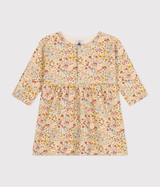 Une robe pour bébé à col rond, couleur crème et motif de petites fleurs colorées.