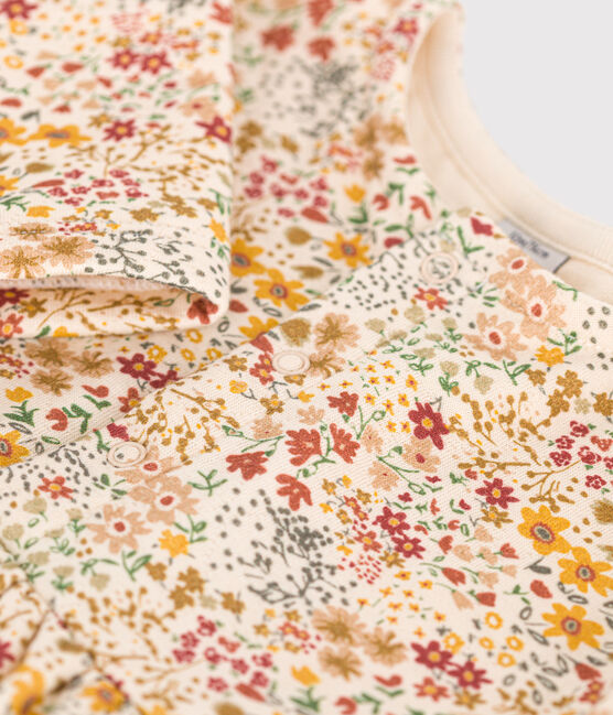 Une robe pour bébé à col rond, couleur crème et motif de petites fleurs colorées.