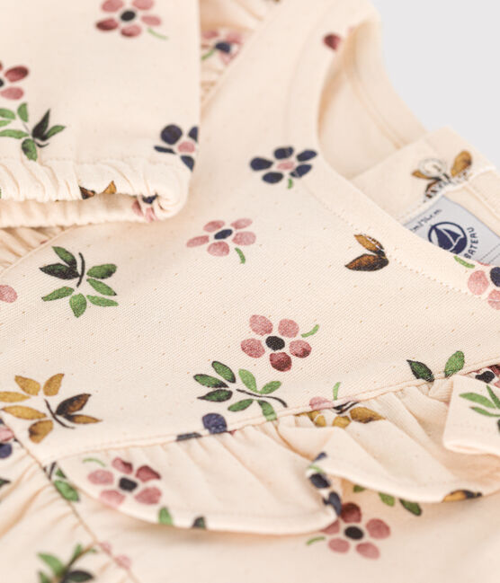 Une robe pour bébé beige et fleurie rosé, vert et bleu, avec des volants sur la poitrine.