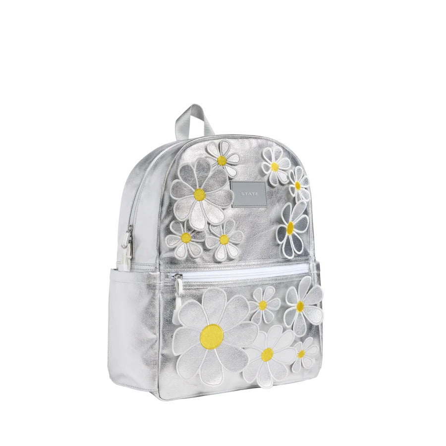 Sac à dos argenté avec une poche à zipper sur le devant et des marguerites en 3D sur l'ensemble.
