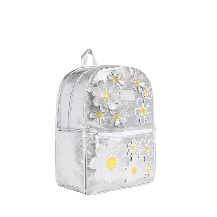 Un sac à dos argent métallique avec une poche à zipper sur le devant et des marguerites en 3D.