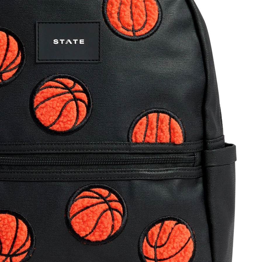 Un sac en texture de cuir noir avec des patched en peluches orange de basketballs.