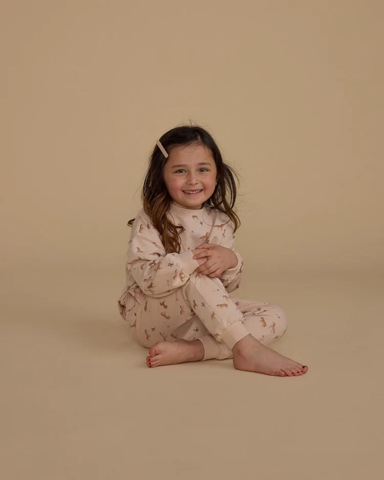 Fillette portant un ensemble de jogging et chandail rose à motif de chevaux.