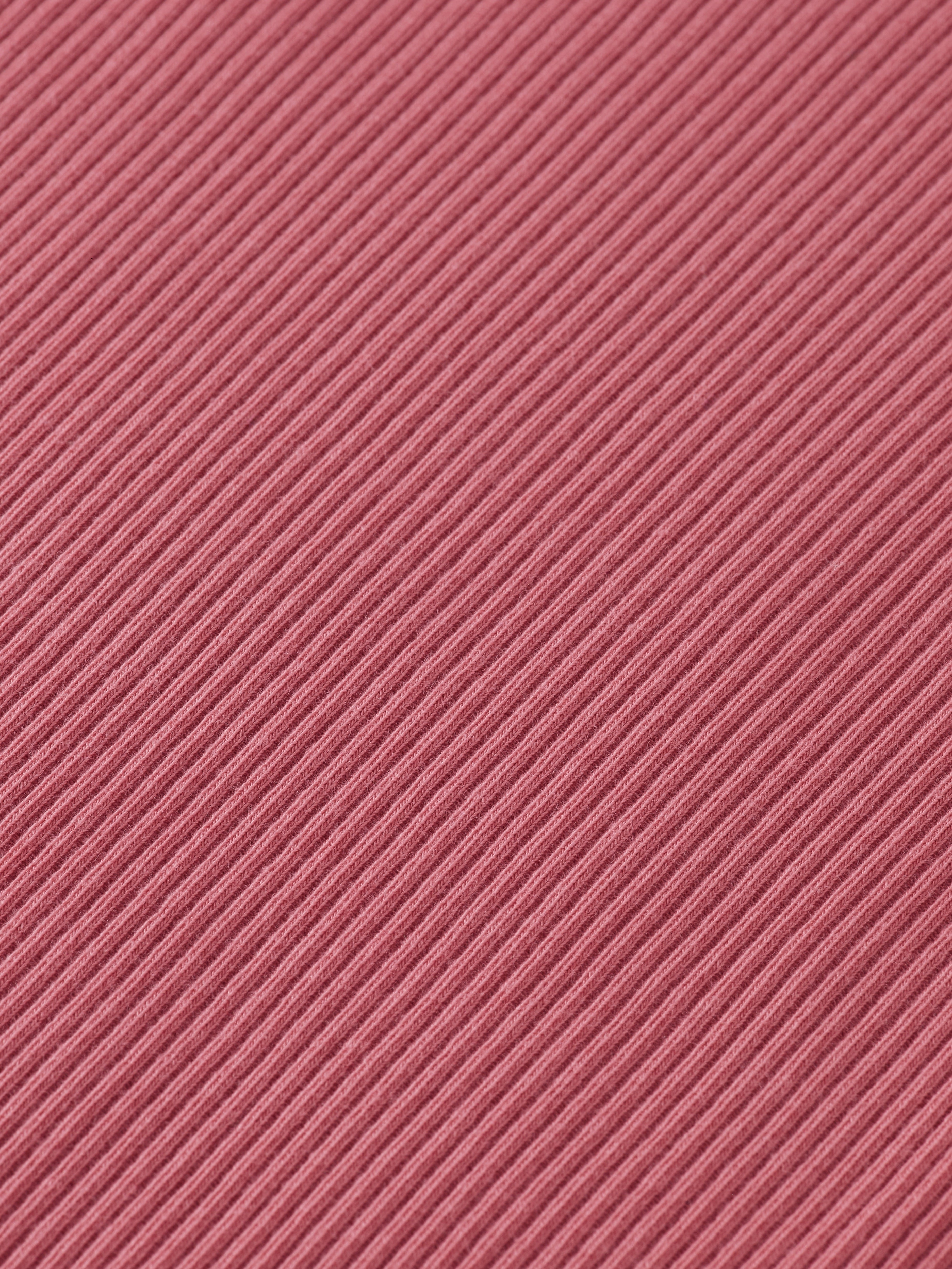 Zoom sur la texture côtelé d'un tissu rose.