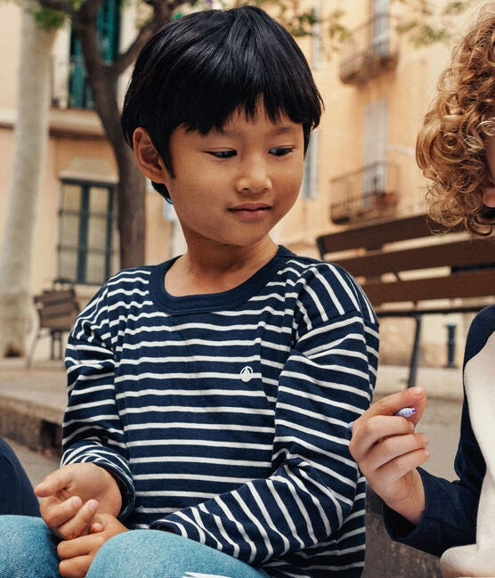 Un t-shirt à manches longues rayé blanc et noir, avec logo brodé de Petit Bateau sur la poitrine.