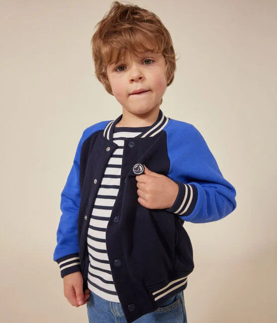 Une veste style Teddy aux manches bleu éclatant et corps foncé, col rayé blanc et poignet élastique.