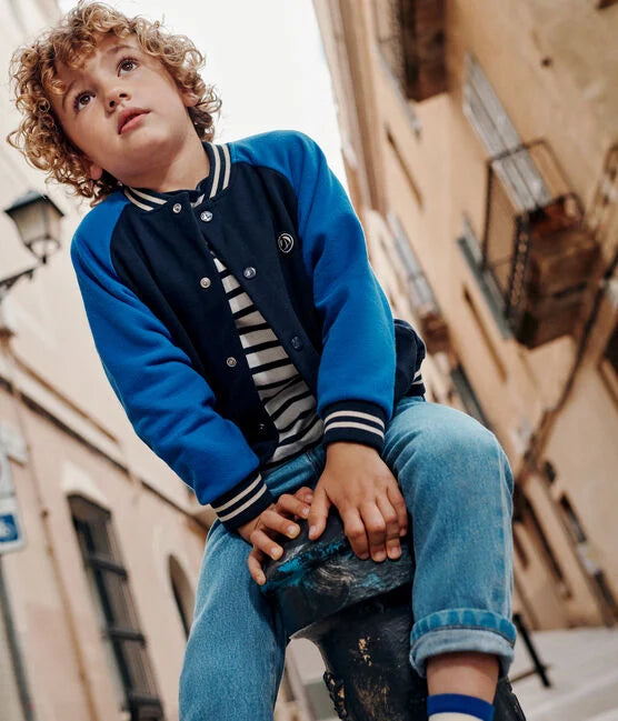 Une veste style Teddy aux manches bleu éclatant et corps foncé, col rayé blanc et poignet élastique.