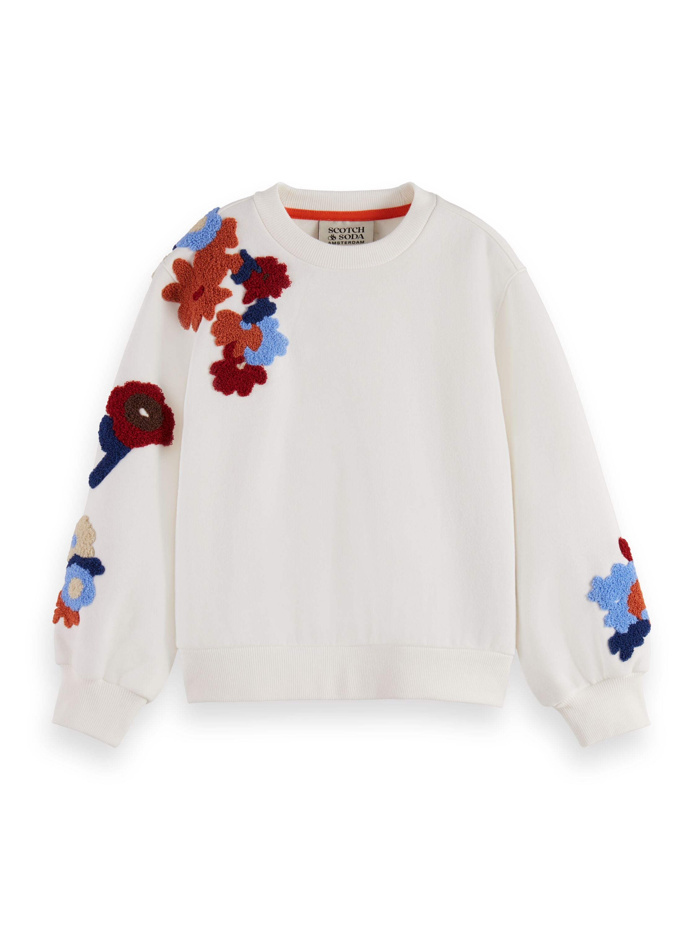 Un crewneck blanc avec des fleurs brodées sur la manche droite et le poignet gauche.
