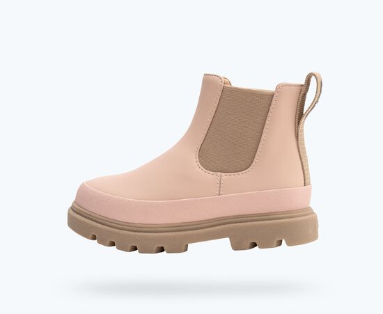 Une botte Chelsea rose millennial avec semelle et panneaux élastiques bruns.