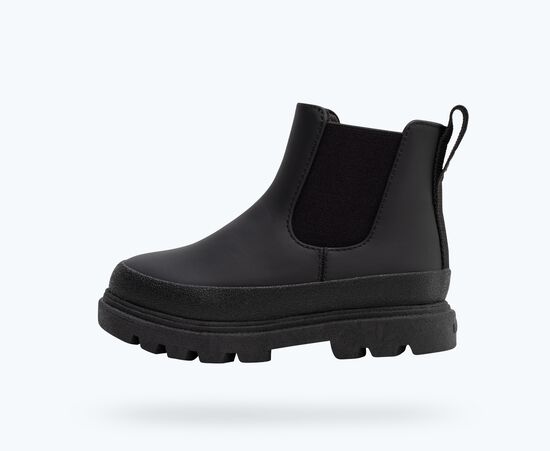 Une botte Chelsea noire avec semelle et panneaux élastiques noirs.