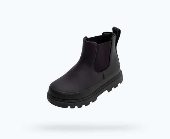 Une botte Chelsea noire avec semelle et panneaux élastiques noirs.