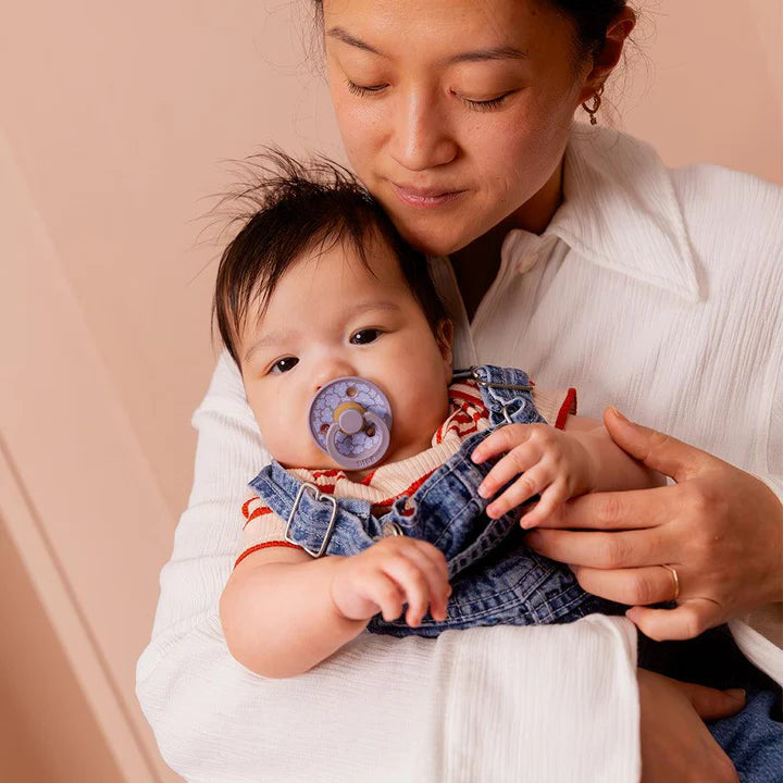 Un bébé utilisant une suce à motif de fleurs bleues.