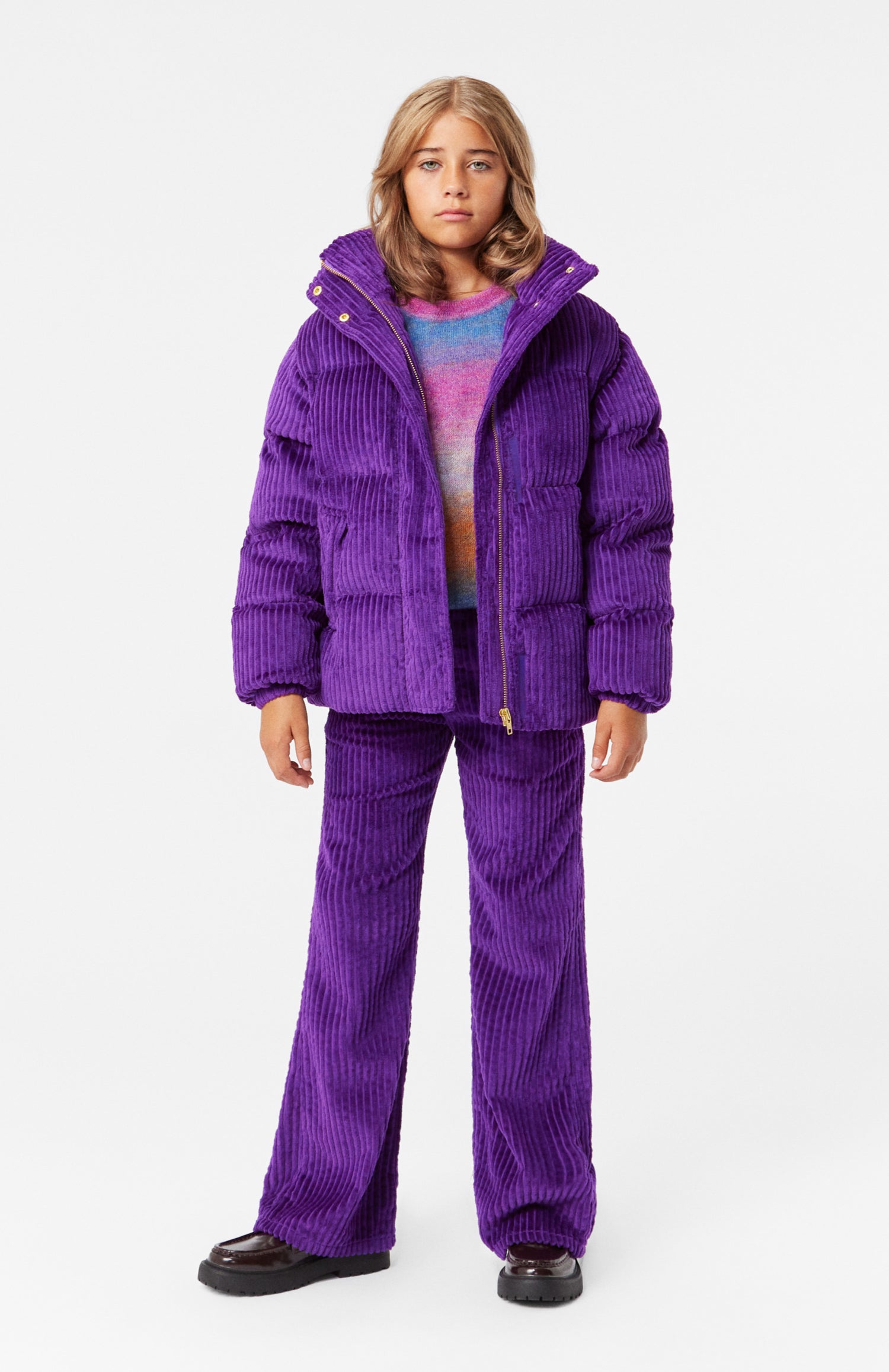 Une jeune fille portant un ensemble pour l'extérieur, dont le pantalon en corduroy.