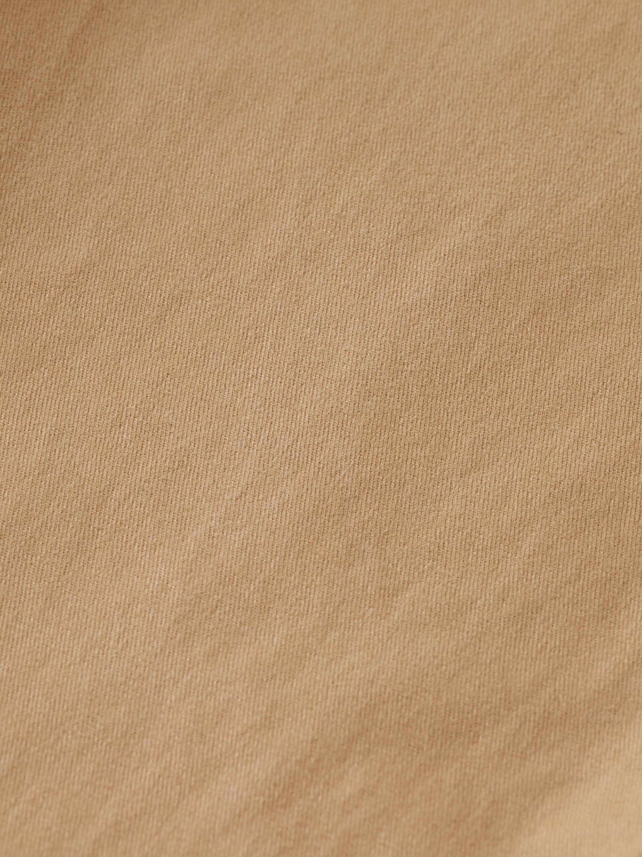 Zoom sur la texture lisse d'un pantalon chino de couleur sable.