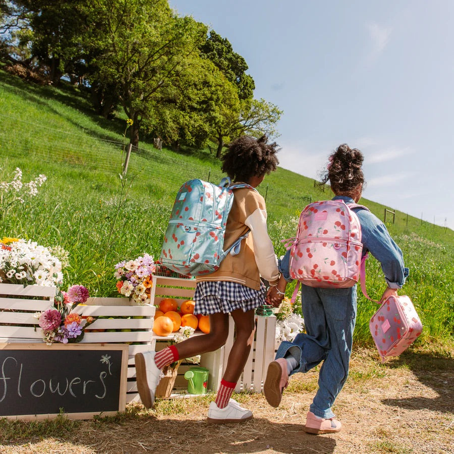 Deux fillettes courant dehors avec des sacs à dos colorés.