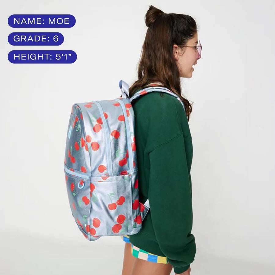 Une jeune fille de 5'1'' portant le sac à dos à cerises, couvrant l'entièreté de son dos.