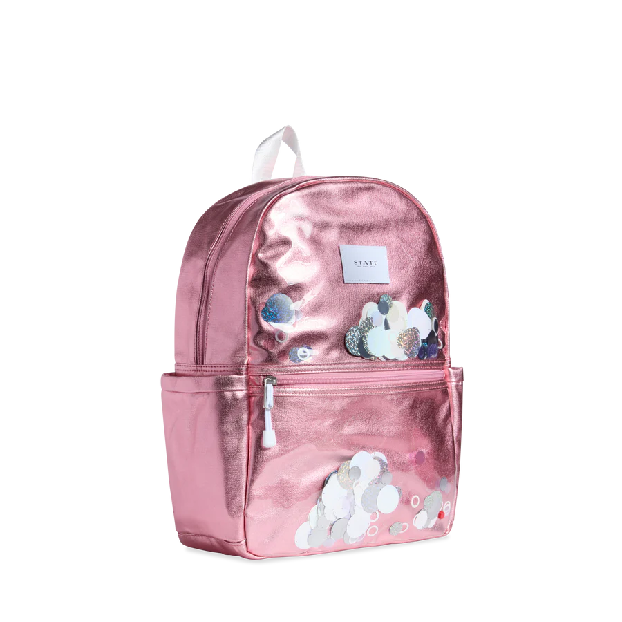 Un sac à dos rose métallique avec des rondelles blanches brillantes sur le devant.