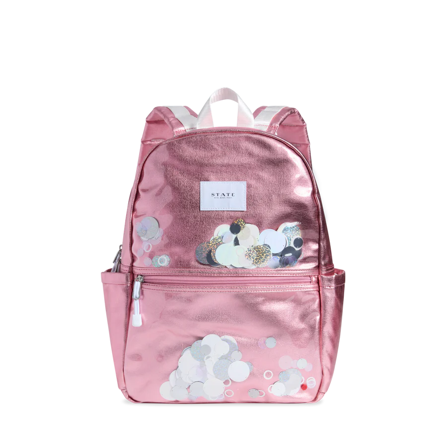 Un sac à dos rose métallique avec des rondelles blanches brillantes sur le devant.