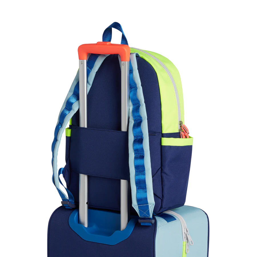Un sa à dos bleu et vert néon accroché sur une valise.