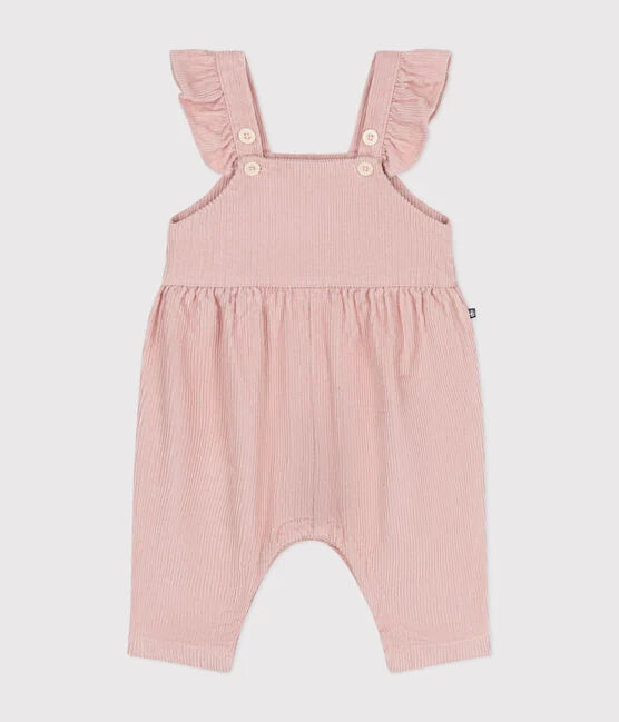 Salopette pour bébé en velours rose avec volant sur les bretelles et ouverture à boutons.
