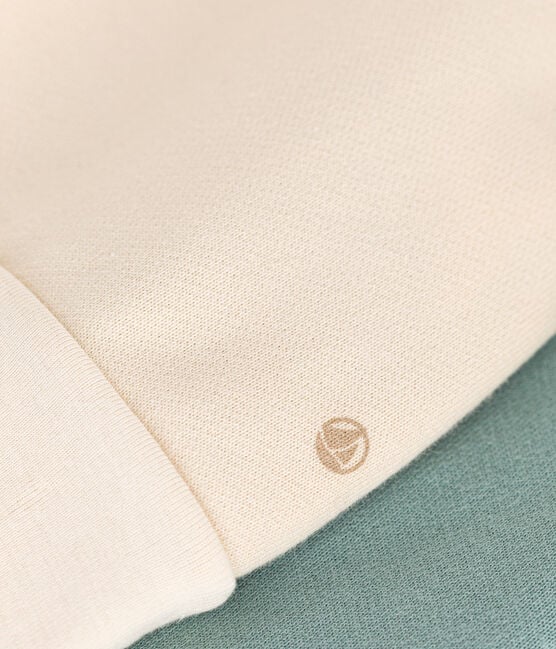 Un tissu beige montrant un petit logo Petit Bateau brodé.