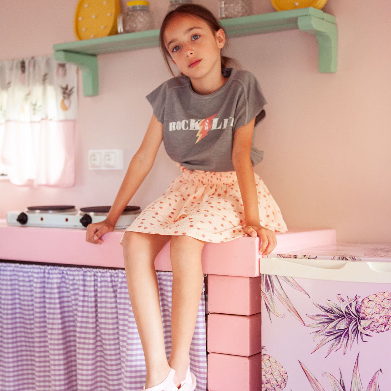 Fille assise sur un comptoir habillée en tocoto vintage, une marque disponible chez Billie Le Kid.